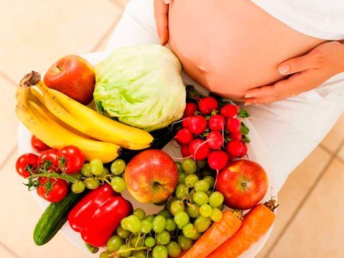 Беременная кушает фрукты и овощи